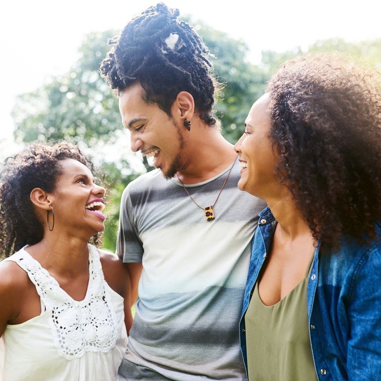 Three partners laughing together outdoors